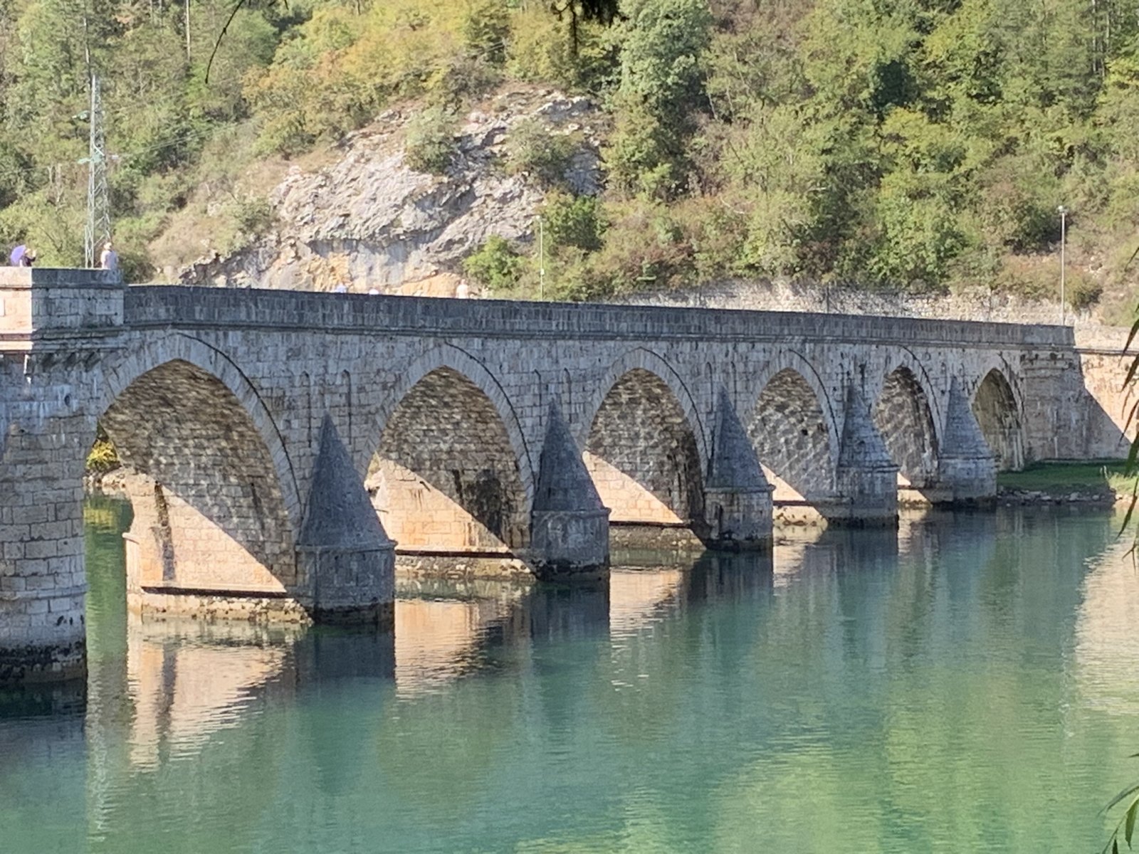 Historic stone bridge with repeated arches across turquoise water